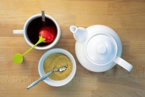 Infused tea, teapot and brown sugar next to each other on beech wood, shot from top